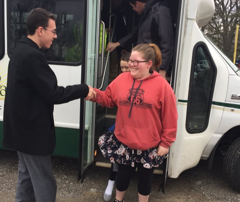 A Grace Baptist Church leader welcoming a rider from the church bus